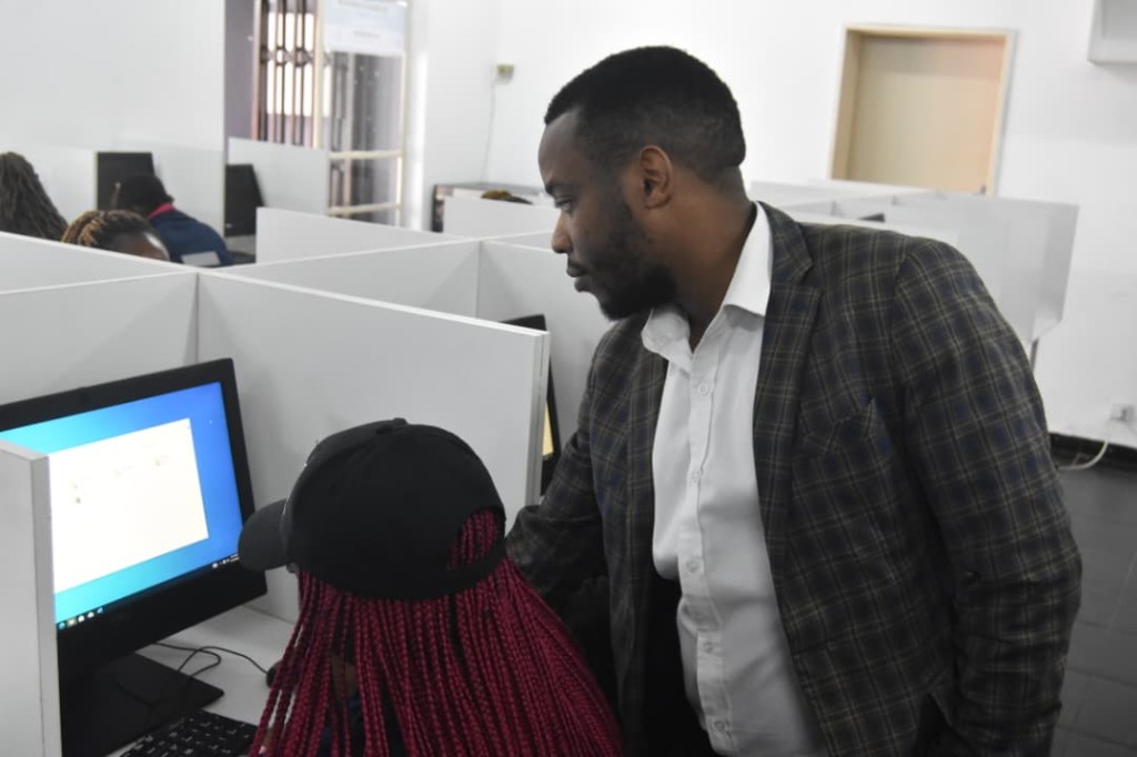 Head of IT Reconcile Makamure with a student in the upgraded computer lab